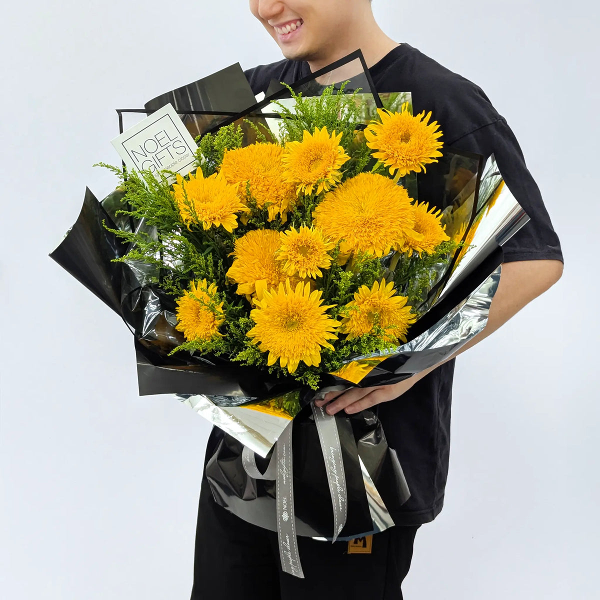 Man holding Born to Shine Classic Hand Bouquet with golden teddy bear sunflowers and yellow phoenix