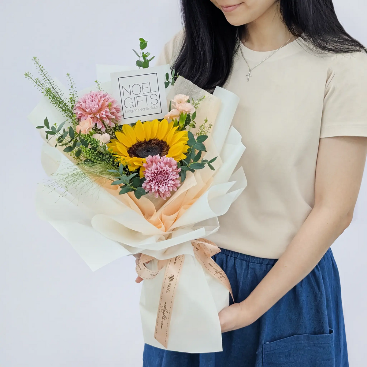 A lady holding a Petite Hand Bouquet featuring a golden sunflower, cream peach dahlia