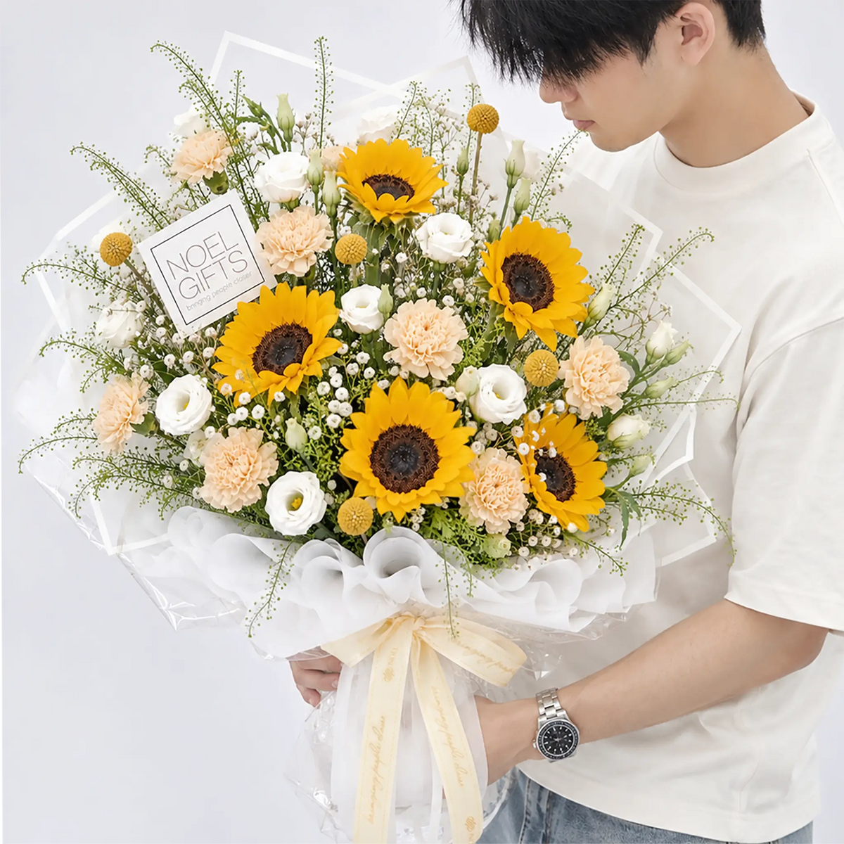 Hand bouquet featuring 4 sunflowers, 5 white eustomas, 8 champagne carnations, Baby’s Breath, Lepidium and Crespedia goeringii foliage | Noel Gifts