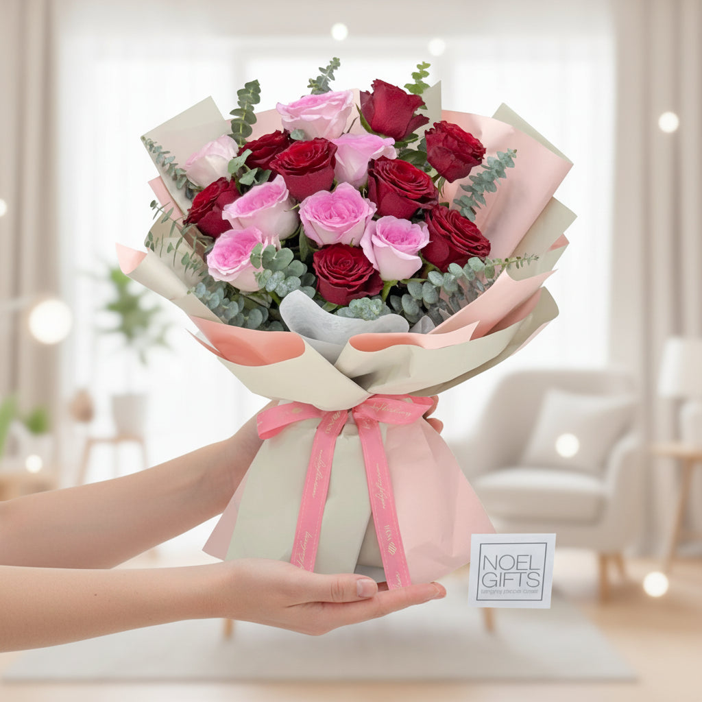 Bouquet of red and pink roses with a pink ribbon on a white background, featuring 'Noel Gifts' branding.