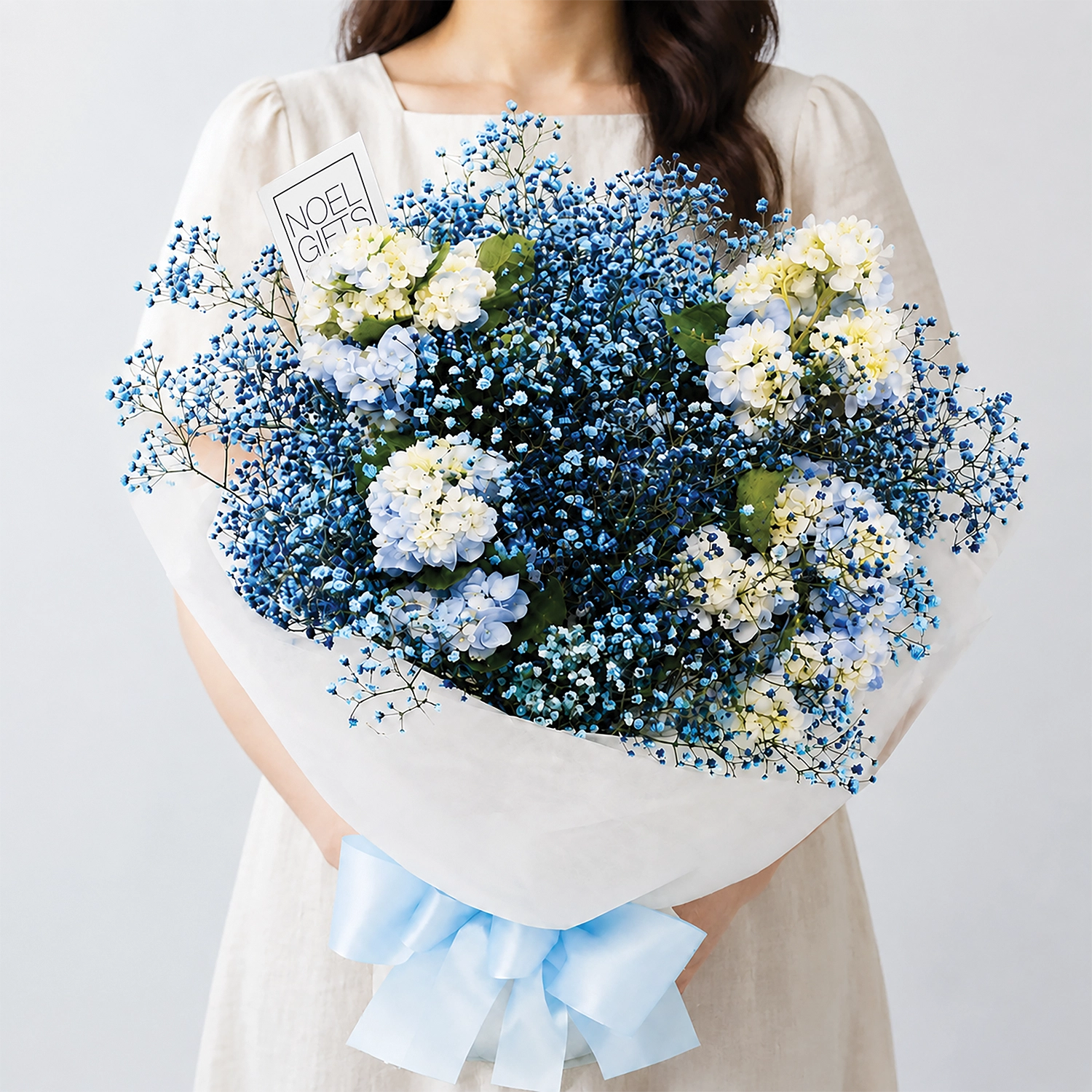Sapphire Flower Hand Bouquet with blue baby’s breath and preserved hydrangea in white wrapping with a light blue satin ribbon